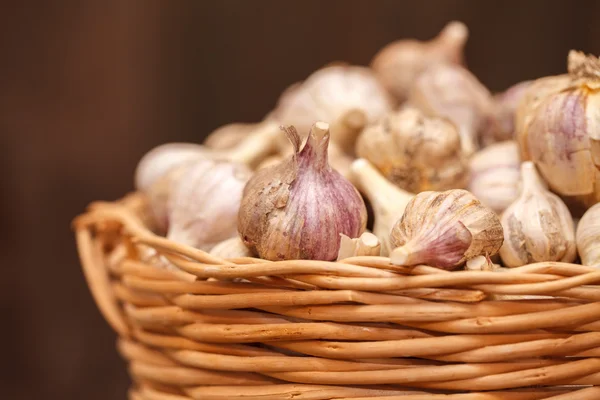 Cabezas de ajo en una canasta de mimbre sobre un fondo de madera — Foto de Stock