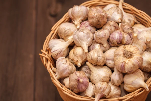 Cabezas de ajo en una canasta de mimbre sobre un fondo de madera — Foto de Stock