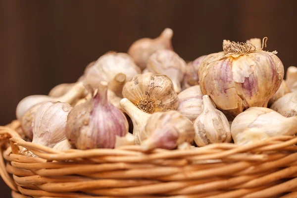 Cabezas de ajo en una canasta de mimbre sobre un fondo de madera — Foto de Stock