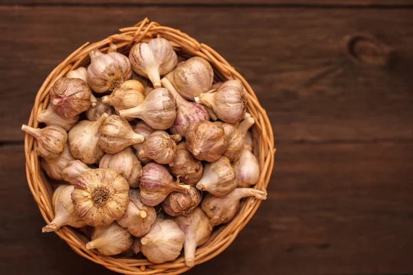 Cabezas de ajo en una canasta de mimbre sobre un fondo de madera — Foto de Stock