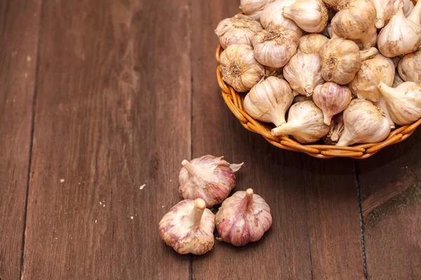 Cabezas de ajo en una canasta de mimbre sobre un fondo de madera —  Fotos de Stock