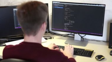 genç adam programcı bir klavye kodu yazarak. Arkadan Görünüm. Odak üstünde belgili tanımlık perde.