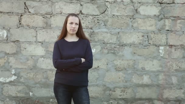 A beautiful girl standing at the concrete wall. Looking into the camera — Stock Video