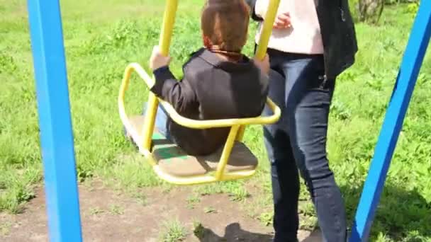 Mamma scuote il bambino figlio su un'altalena nel parco — Video Stock