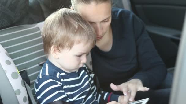 Mãe e filho usando tablet sentado no banco de trás do carro . — Vídeo de Stock