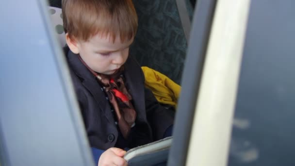 Niño pequeño usando una tableta sentada en un coche de asiento de coche — Vídeo de stock