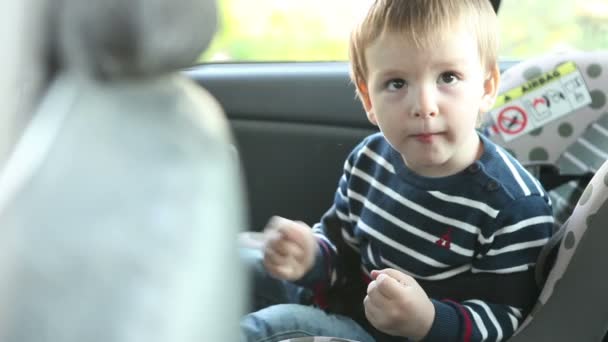 Bambino utilizzando un tablet seduto in un seggiolino auto — Video Stock