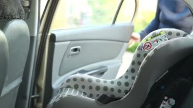 Kadın çocuk araba koltuğuna koyar. Anne ve oğlu