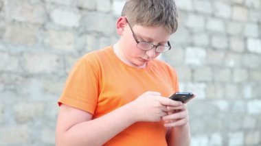 Çocuk bir smartphone bir ileti yazar. Açık havada