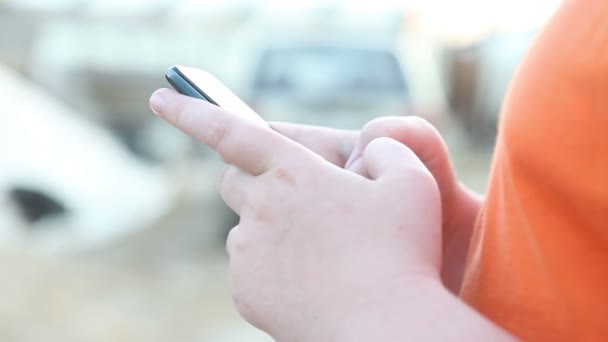 Αγόρι είναι πληκτρολογώντας ένα μήνυμα στο τηλέφωνο. Χέρια γκρο πλαν — Αρχείο Βίντεο