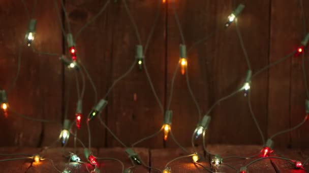 Blinkende Girlanden liegen auf dem Holzboden. Weihnachtlicher Hintergrund — Stockvideo