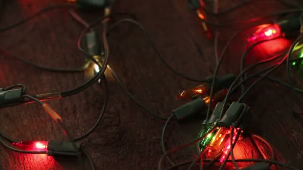 Blinkende Girlanden liegen auf dem Holzboden. Weihnachtlicher Hintergrund — Stockvideo