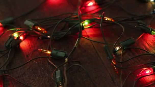 Flashing garland lying on the wooden floor. Christmas background — Stock Video