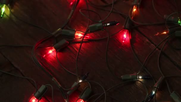 Blinkende Girlanden liegen auf dem Holzboden. Weihnachtlicher Hintergrund — Stockvideo