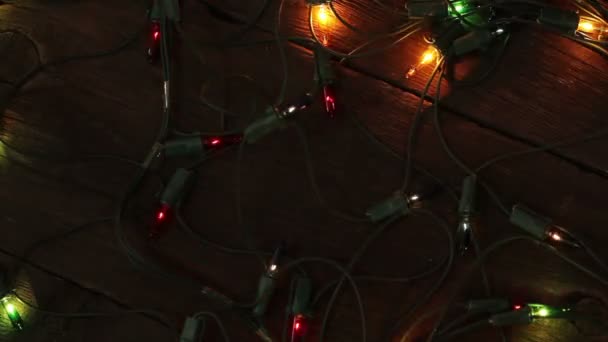 Сверкающие гирлянды лежат на деревянном полу. Рождественский фон — стоковое видео
