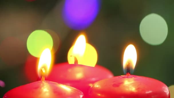 Drei brennende Kerzen auf einem Hintergrund blinken Girlanden — Stockvideo