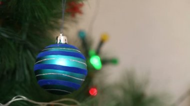 Mavi top bir Noel ağacına sallanıyor.