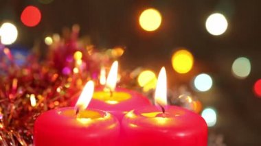 Noel süsleri. Çelenk yanıp sönen arka plan üzerinde yanan mumlar ve oyuncaklar.