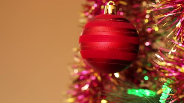 Red ball on the Christmas tree with blinking garlands in tinsel. — Stock Video