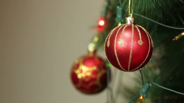 Rote Kugeln auf einem Weihnachtsbaum mit blinkenden Girlanden — Stockvideo