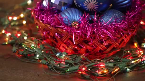 Blaue Kugeln in einem Weidenkorb und Girlanden blinken. Weihnachtlicher Hintergrund — Stockvideo
