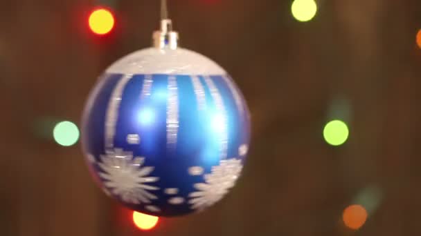 Blaue Weihnachtskugel auf dem Hintergrund blinkt verschwommene Girlande. — Stockvideo