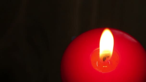 Горящая свеча в красном воске на темном фоне . — стоковое видео