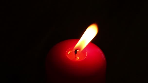 Burning candle in red wax on a dark background. — Stock Video