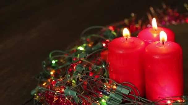 Drie brandende Kerst kaarsen omringd door garland knippert. Achtergrond — Stockvideo