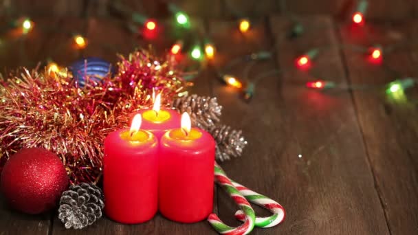 Decoraciones navideñas. Velas ardientes y juguetes en el fondo de guirnaldas parpadeando . — Vídeo de stock