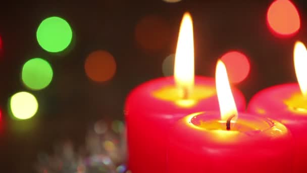 Drie brandende Kerst kaarsen. Onscherpe achtergrond met Kerstmis garland — Stockvideo