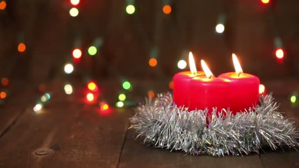 Three burning Christmas candles. Blurred background with Christmas garland — Stock Video