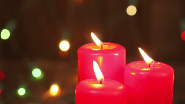 Три горящие рождественские свечи. Размытый фон с рождественской гирляндой — стоковое видео