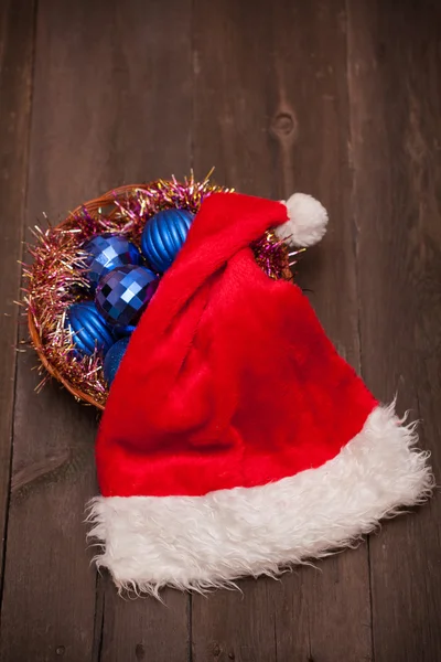 Noel Baba şapkaları ve ahşap bir zemin üzerine mavi Noel topları — Stok fotoğraf