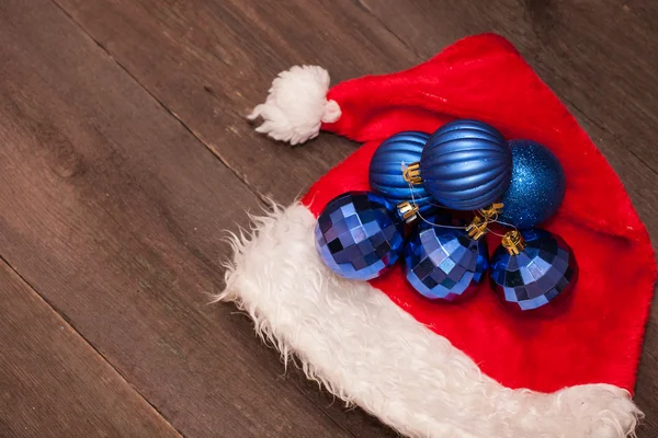 Sombreros de Santa y bolas azules de Navidad sobre un fondo de madera — Foto de Stock