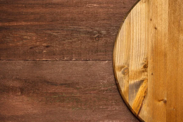 Part of a round cutting board on a wooden background — Stock Photo, Image