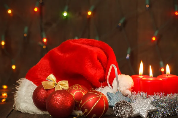 Drie brandende kaarsen en Santa hoeden. Kerstmis achtergrond — Stockfoto