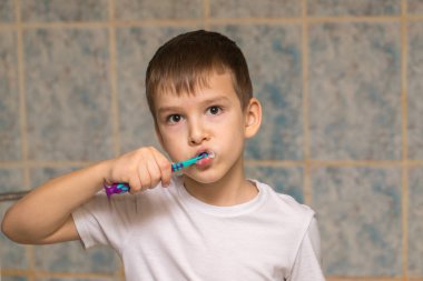 Altı yaşında bir çocuk banyoda dişlerini fırçalıyor. yakın plan portre