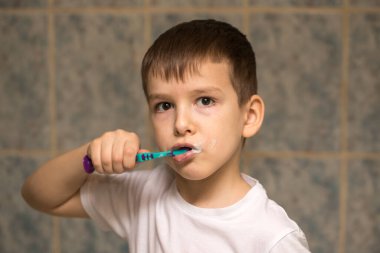 Altı yaşında bir çocuk banyoda dişlerini fırçalıyor. yakın plan portre