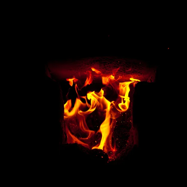 Des flammes jaillissent de la chambre de combustion du four, sur fond noir — Photo
