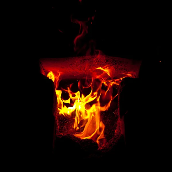 Des flammes jaillissent de la chambre de combustion du four, sur fond noir — Photo