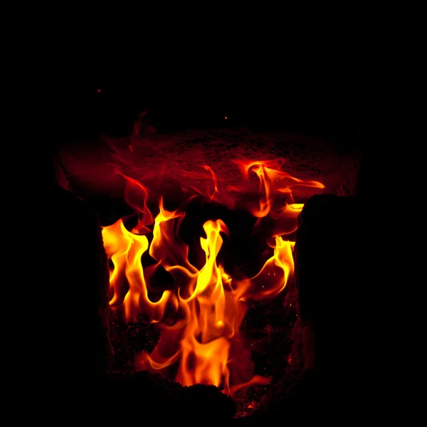 Des flammes jaillissent de la chambre de combustion du four, sur fond noir — Photo