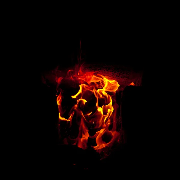 Des flammes jaillissent de la chambre de combustion du four, sur fond noir — Photo