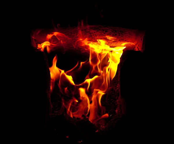 Des flammes jaillissent de la chambre de combustion du four, sur fond noir — Photo