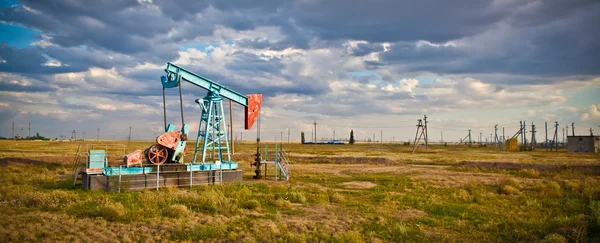 Yağ pompası fırtınalı gökyüzü arka plan üzerinde panorama