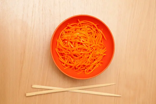 Korean carrots on a plate next to chopsticks — Stock Photo, Image