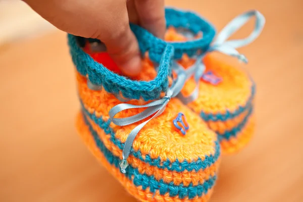 Knitted booties in hand, shallow depth of field — Stock Photo, Image