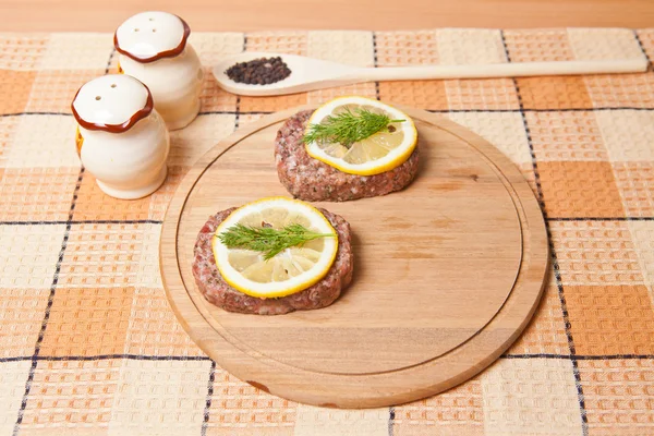 Cutlet with lemon slices on a cutting board next to the saucepan — Stock Photo, Image