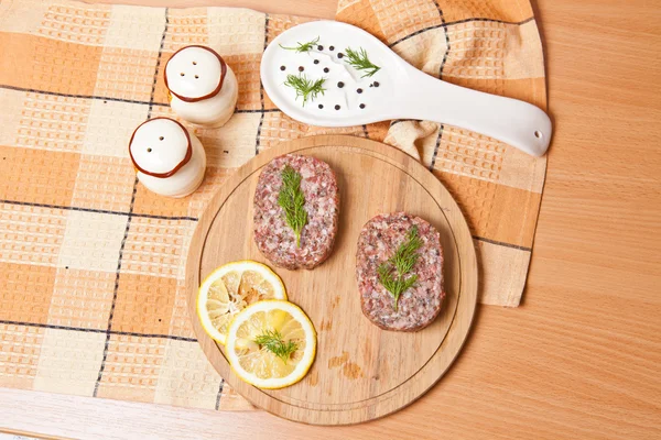 Cutlet with lemon slices on a cutting board next to the saucepan — Stock Photo, Image