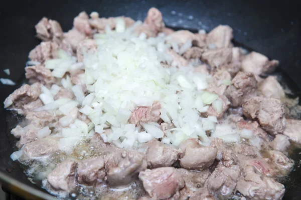 Partes de carne com cebolas fritas em uma panela — Fotografia de Stock